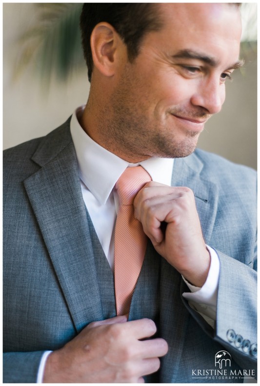 Groom putting on his coral tie | Scripps Seaside Forum Wedding | La Jolla San Diego Wedding Photographer | Kristine Marie Photography | © www.kristinemariephotography.com