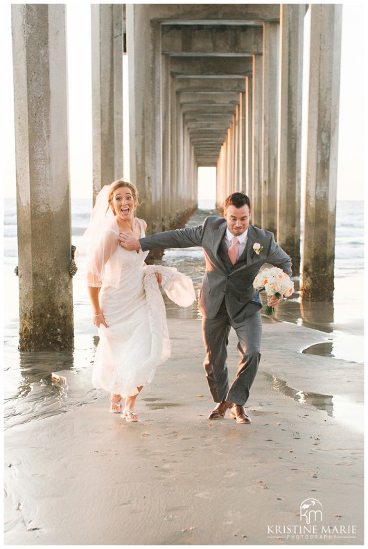 bride and groom race under pier | Scripps Seaside Forum Wedding | La Jolla San Diego Wedding Photographer | Kristine Marie Photography | © www.kristinemariephotography.com